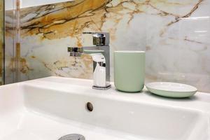 lavandino del rubinetto dell'acqua in metallo con rubinetto con distributori di sapone e shampoo in un bagno costoso foto