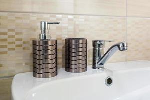 lavandino del rubinetto dell'acqua in ceramica con rubinetto con distributori di sapone e shampoo in costosi bagni o cucine a soppalco foto