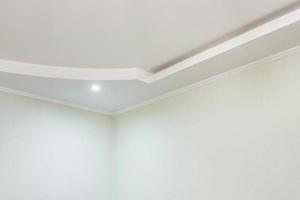 dettaglio di angolo soffitto con intricato corona modanatura. sospeso soffitto e cartongesso costruzione nel vuoto camera nel appartamento o Casa. allungare soffitto bianca e complesso forma. foto