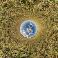 palla di cielo blu nel mezzo del campo vorticoso. inversione del minuscolo pianeta trasformazione del panorama sferico a 360 gradi. curvatura dello spazio. foto