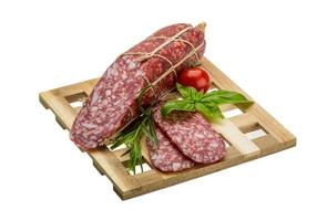 salame su di legno piatto e bianca sfondo foto