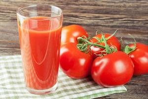 succo di pomodoro e pomodori freschi sulla tavola di legno foto