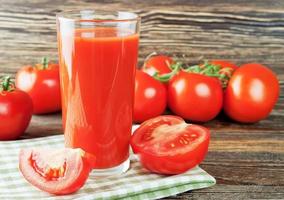 succo di pomodoro e pomodori freschi sulla tavola di legno foto