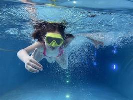 sorridente bambino nel occhiali nuotare, tuffo nel il piscina con divertimento - saltare in profondità giù sott'acqua. salutare stile di vita, persone acqua sport attività su estati. foto