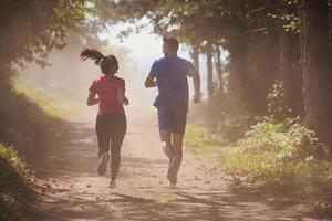 coppia godendo nel un' salutare stile di vita mentre jogging su un' nazione strada foto