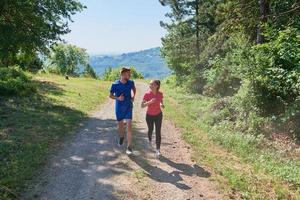 coppia godendo nel un' salutare stile di vita mentre jogging su un' nazione strada foto