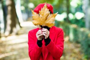 anonimo donna copertura viso con autunno foglia foto