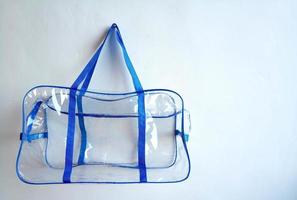 plastica Borsa con blu maniglie sospeso su un' chiodo, su un' bianca sfondo foto