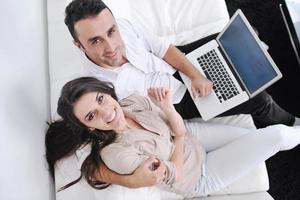gioioso coppia rilassare e opera su il computer portatile computer a moderno casa foto