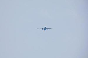 commerciale aereo volante sotto blu cieli e in arrivo a il aeroporto foto