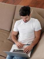 uomo rilassante su divano con il computer portatile foto