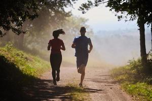 coppia godendo nel un' salutare stile di vita mentre jogging su un' nazione strada foto
