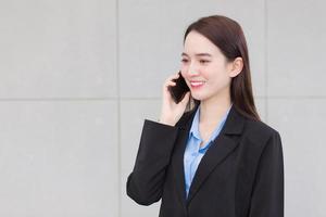 asiatico professionale attività commerciale donna indossa nero completo da uomo mentre utilizzando un' smartphone per importante attività commerciale. foto