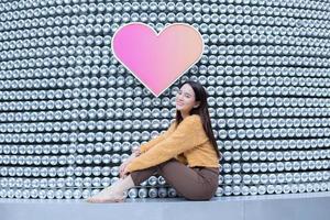 la bella donna asiatica con i capelli lunghi indossa un maglione giallo e sorride brillantemente in tema di San Valentino. foto