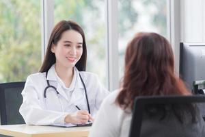 asiatico donna paziente anziano consulta con donna medico di il suo sintomo mentre medico dà assistenza sanitaria informazione con lui a Ospedale. foto