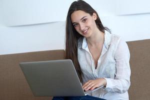 rilassato giovane donna a casa Lavorando su il computer portatile computer foto