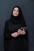 giovane arabo donna d'affari nel tradizionale Abiti o abaya con tavoletta computer foto