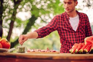 uomo mettendo spezie su crudo carne per barbecue foto