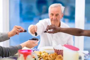 moderno multietnico musulmano famiglia condivisione un' ciotola di date foto