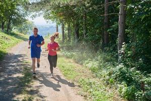 coppia godendo nel un' salutare stile di vita mentre jogging su un' nazione strada foto