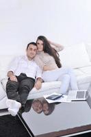 gioioso coppia rilassare e opera su il computer portatile computer a moderno casa foto