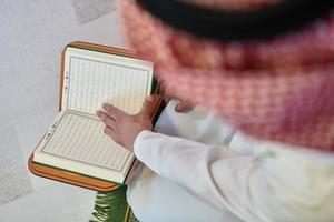 giovane musulmano uomo lettura Corano durante Ramadan foto