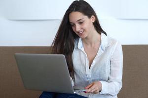 rilassato giovane donna a casa Lavorando su il computer portatile computer foto