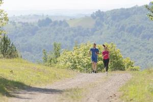 coppia godendo nel un' salutare stile di vita mentre jogging su un' nazione strada foto