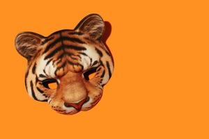 arancia tigre a strisce masquerade viso maschera con realistico Stampa di gattopardo museruola. carnevale bambini maschera per vacanza festa. arancia sfondo con copia spazio. foto