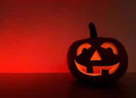 lavorato raggiante zucca sta su il superficie nel buio notte. il indietro parete con posto per testo è evidenziato nel rosso. Halloween vacanza sfondo con tradizionale sorridente jack-o-lantern. foto