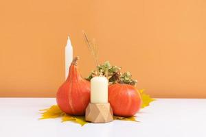 composizione creativa autunnale. ghirlanda di foglie secche, zucche e candela su sfondo bianco arancione. concetto di autunno autunno e giorno del ringraziamento. natura morta foto