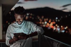 il giovane uomo su un urbano città strada a notte sms su smartphone con bokeh e neon città luci nel il sfondo.