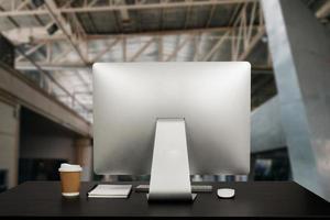 computer dell'area di lavoro che mette su una scrivania in legno e circondato da tazza di caffè, appunti, pianta in vaso, pila di smartphone, tablet e ufficio ordinato con tastiera. foto