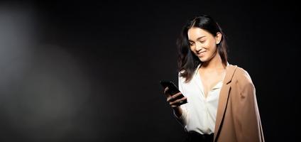 metà corpo ritratto di asiatico bellissimo donna indossare bianca camicia, utilizzando Internet inteligente Telefono foto