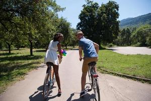 giovane coppia multietnica che fa un giro in bicicletta nella natura foto