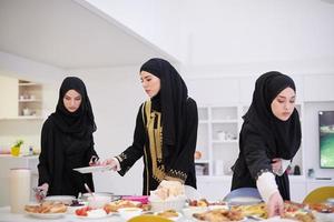 giovane musulmano ragazze servendo cibo su il tavolo per iftar cena foto