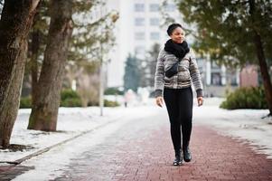 africano donna indossare nel nero sciarpa passeggiate su il sentiero nel inverno giorno a Europa. foto