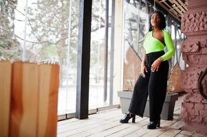 alla moda africano americano donna nel un' leggero verde superiore e nero pantaloni posa. foto