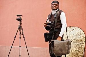 giovane professionale africano americano operatore video Tenere professionale telecamera con professionista attrezzatura. afro cineoperatore indossare nero duraq fabbricazione un' video. foto