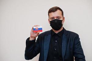 europeo uomo indossare nero formale e proteggere viso maschera, hold slovacchia bandiera carta isolato su bianca sfondo. Europa coronavirus covid nazione concetto. foto