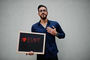 io amore Egitto. mezzo orientale uomo indossare blu camicia, occhiali, hold tavola. foto