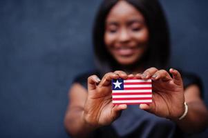 orgoglioso per essere liberiano. africano donna hold piccolo Liberia bandiera nel mani. foto