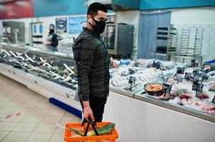 asiatico uomo indossare nel protettivo viso maschera shopping nel supermercato durante pandemia. scegliere frutti di mare. foto