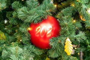 Natale abete albero decorato con rosso e d'oro palline con 2021 numeri. luminosa festivo vacanza decorazione. sfocato sfondo.all'aperto ornato ringhiere. nuovo anno fondale foto