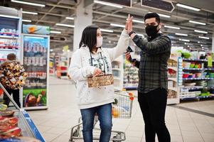 asiatico coppia indossare nel protettivo viso maschera shopping insieme nel supermercato durante pandemia. Tenere torta e vino per festa. foto