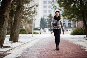 africano donna indossare nel nero sciarpa passeggiate su il sentiero nel inverno giorno a Europa. foto