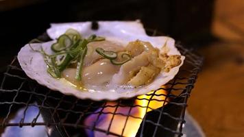 fresco giapponese pettine hotate con conchiglia su il griglia con fiamme nel ristorante hokkaido, Giappone foto
