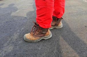 salutare sicurezza e ambientale ufficiali chi indossare rosso pantaloni uniformi e Marrone sicurezza scarpe. foto