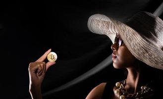 silhouette di giovane donna hold oro bitcoin criptovaluta commercio in linea al di sopra di drappo tenda nero foto