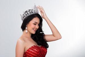 ritratto di Perdere spettacolo concorso nel asiatico rosso lustrino sera palla toga vestito con argento diamante corona fascia, moda rendere su viso capelli stile, studio illuminazione bianca sfondo isolato copia spazio foto